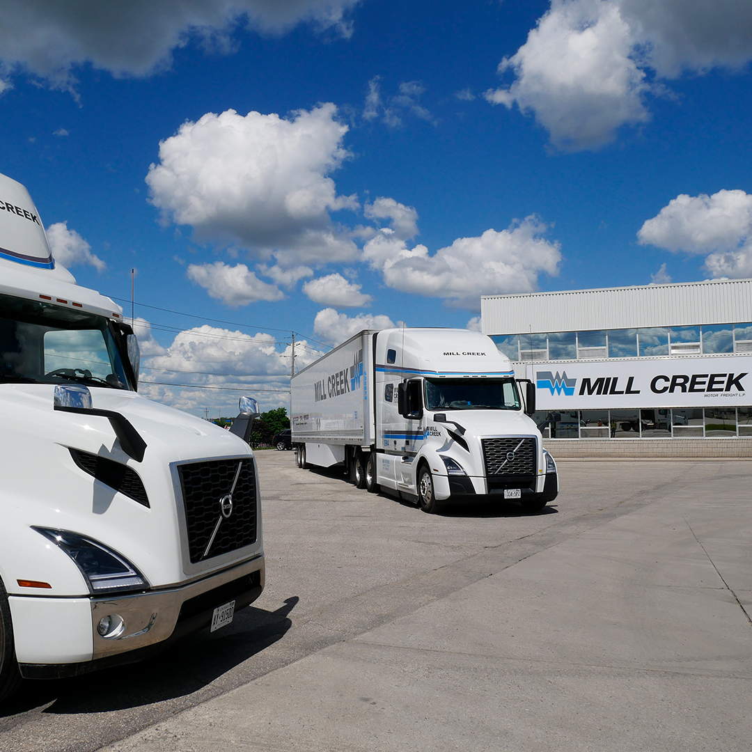 Mill Creek Trucks and Office Signage Two Mill Creek Motor Freight Volvo trucks parked by the office with large branded signage.