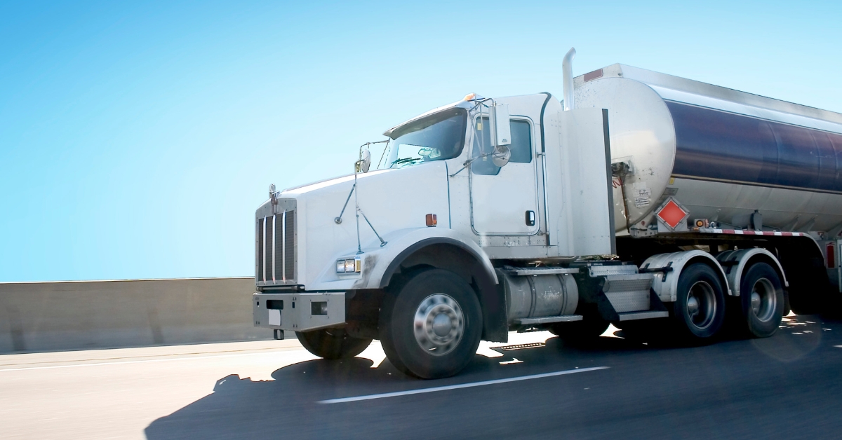 White tank truck equipped with ISAAC Instruments telematics solutions driving on a highway, symbolizing advanced fleet management for safety and efficiency.
