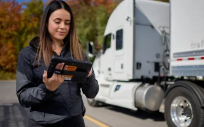 A truck driver examines a handheld ISAAC Instruments device, ready to employ advanced fleet management technology on the road.