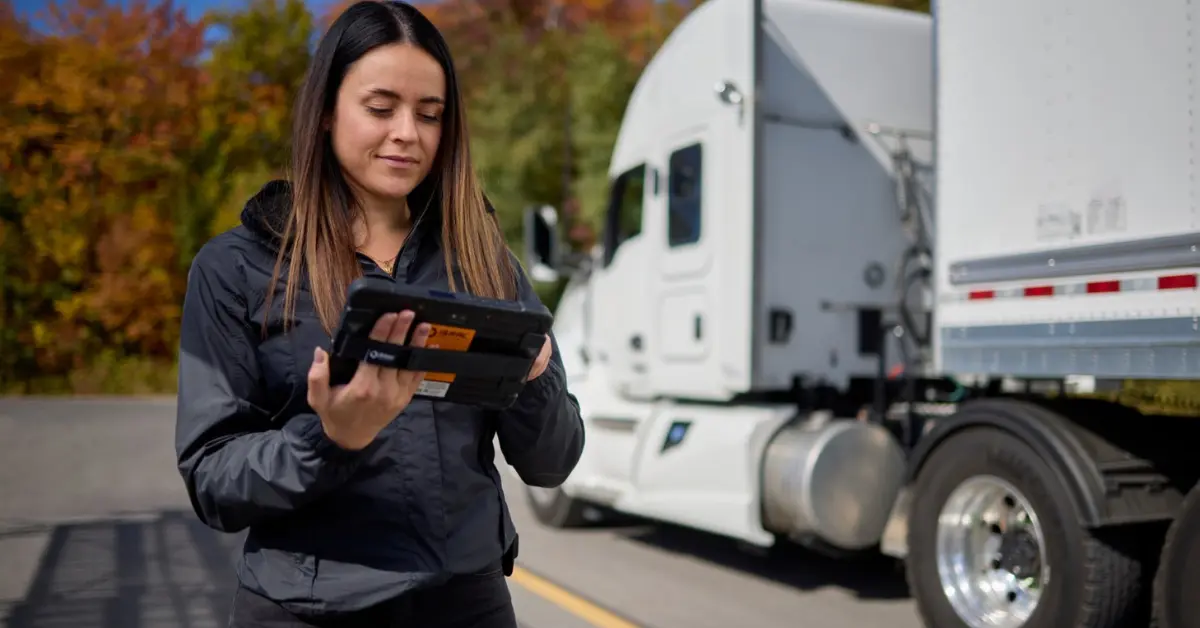 A truck driver examines a handheld ISAAC Instruments device, ready to employ advanced fleet management technology on the road.