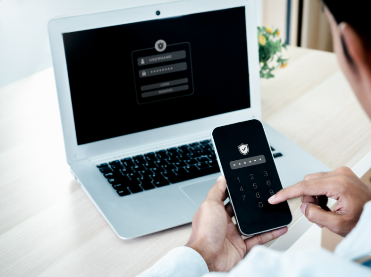 Person using multi-factor authentication on a smartphone and laptop.