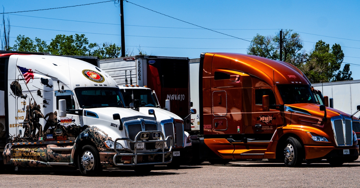 Two Navajo Express trucks, one wrapped in a military tribute honoring veterans, showcasing the fleet's partnership with ISAAC Instruments