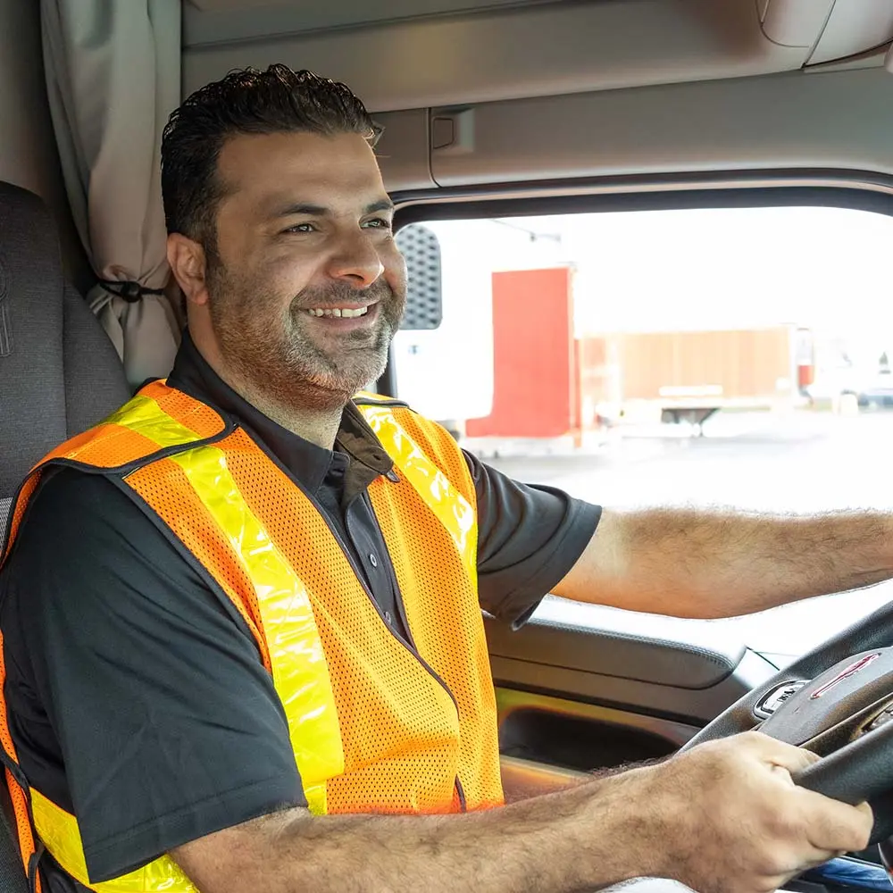 Happy Driver Using ISAAC System Smiling truck driver wearing safety vest inside vehicle