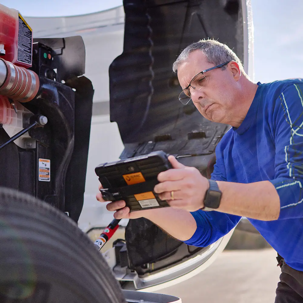 Conducting DVIR Inspections with ISAAC Tablet Technician using ISAAC tablet during vehicle inspection procedure