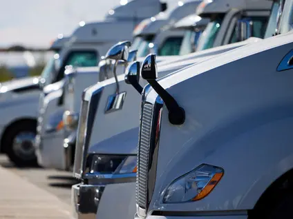 Lineup of white electric freight trucks parked in a row, highlighting clean transportation solutions