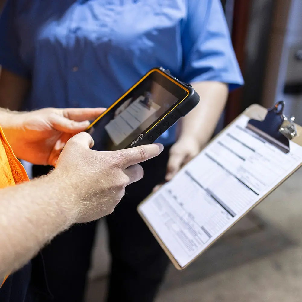 Digital Document Management for Fleet Efficiency Fleet personnel using a rugged tablet to digitize documents beside a paper log clipboard