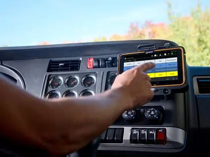 Truck driver using an in-cab tablet to monitor fleet performance data on a digital dashboard