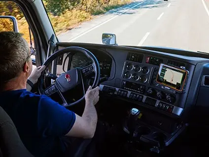 Truck driver using a performance coaching tablet with a white truck in the background