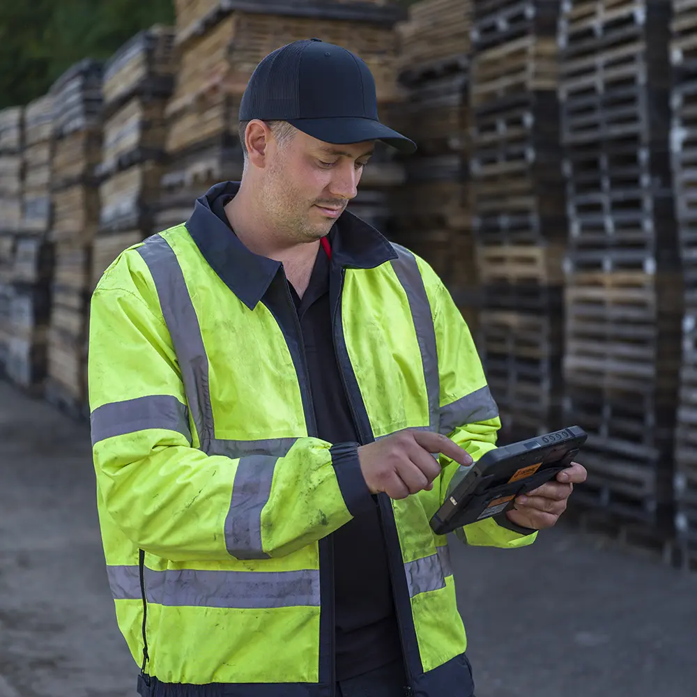 Truck driver using the ISAAC rugged tablet to automate routine tasks and verify workflow compliance in a freight yard.