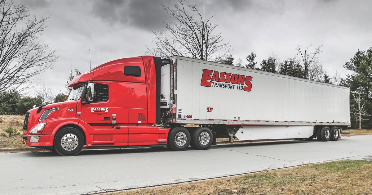 A red Eassons Transport LTD tractor pulls a 53-foot dry van trailer along a tree-lined road.